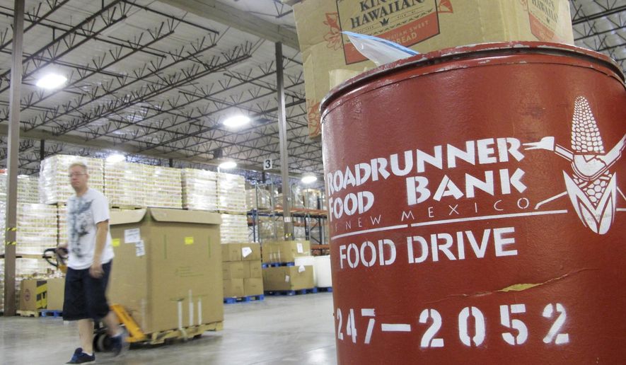 FILE - In this June 21, 2013 file photo a volunteer moves a pallet of food at the Roadrunner Food Bank in Albuquerque, N.M. The food bank distributes about 90,000 pounds of food a day to organizations that help low-income families. A program in New Mexico seeks to help farmers struggling with the economic effects of COVID-19 restrictions while assisting food banks seeking to fight hunger and poverty. (AP Photo/Susan Montoya Bryan, File)