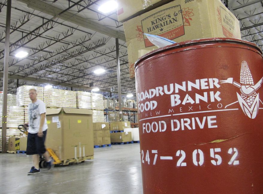 FILE - In this June 21, 2013 file photo a volunteer moves a pallet of food at the Roadrunner Food Bank in Albuquerque, N.M. The food bank distributes about 90,000 pounds of food a day to organizations that help low-income families. A program in New Mexico seeks to help farmers struggling with the economic effects of COVID-19 restrictions while assisting food banks seeking to fight hunger and poverty. (AP Photo/Susan Montoya Bryan, File)