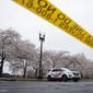 FILE - In this March 23, 2020, file photo a Washington, D.C. Metropolitan Police vehicle is parked on the other side of a tape police line along the Tidal Basin as cherry blossoms cover the trees, in Washington. The nation&#39;s capital, like most of the nation itself, is largely shuttered. (AP Photo/Carolyn Kaster, File)