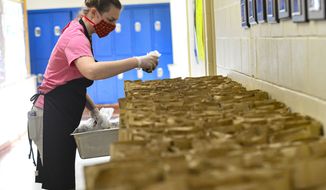 Emma Griffith helps fill brown bags with food items at Twin Vally Middle High School, in Whitingham, Vt., that will be delivered to children around the community on Monday, April 20, 2020. (Kristopher Radder/The Brattleboro Reformer via AP)