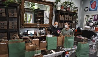 In this Thursday, April 16, 2020, photo, wearing a protective mask and gloves, budtenders prepare orders for customers to pick-up at The Higher Path cannabis dispensary in the Sherman Oaks section of Los Angeles. Monday is April 20, or 4/20. Thats the code for marijuanas high holiday, which is usually marked with outdoor festivals and communal smoking sessions. But this year, stay-at-home orders have moved the party online as the marijuana market braces for an economic blow from the coronavirus crisis. (AP Photo/Richard Vogel)