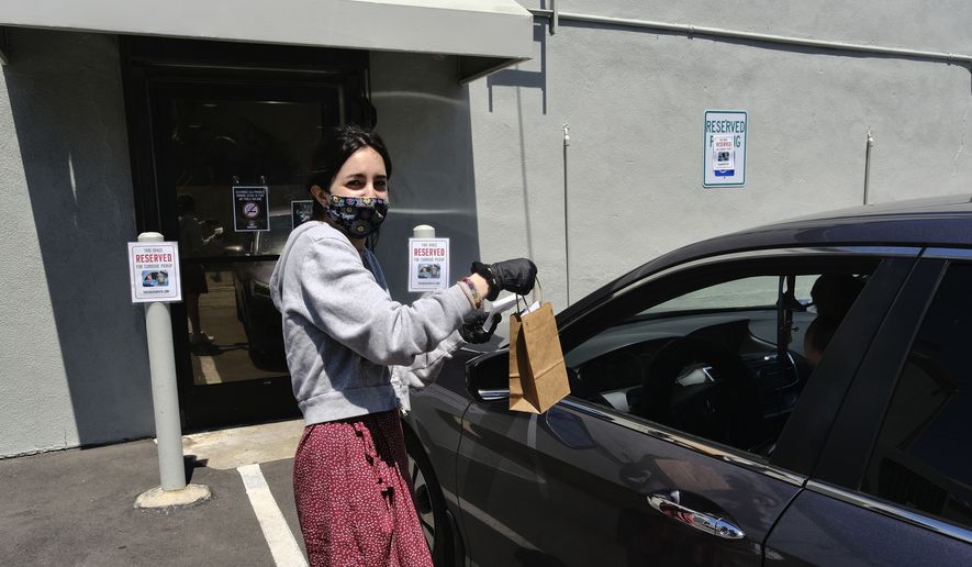 In this Thursday, April 16, 2020, photo, wearing a protective mask and gloves budtender, Alexi Ezdrin attends to a customer in his car with curbside service at The Higher Path cannabis dispensary in the Sherman Oaks section of Los Angeles. (AP Photo/Richard Vogel)