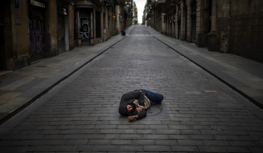 A man sleeps in an empty street during the coronavirus outbreak in Barcelona, Spain, April 17, 2020. (AP Photo/Emilio Morenatti)