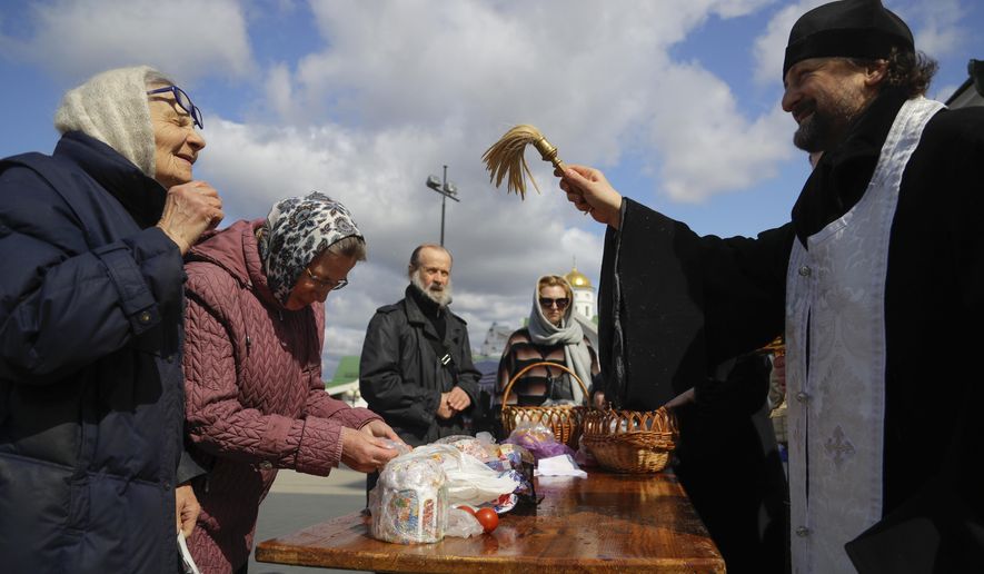 An Orthodox priest blesses traditional Easter cakes and painted eggs in preparation for Easter, outside a church in Minsk, Belarus, Saturday, April 18, 2020. For Orthodox Christians, this is normally a time of reflection, communal mourning and joyful release, of centuries-old ceremonies steeped in symbolism and tradition. But this year, Easter - by far the most significant religious holiday for the world's roughly 300 million Orthodox - has essentially been cancelled. (AP Photo/Sergei Grits)