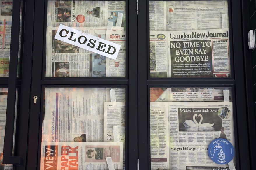 A front page of the Camden New Journal newspaper with a coronavirus related headline hangs stuck with other pages on the closed doors of a restaurant, unable to open due to the coronavirus lockdown, in central London, Monday, April 20, 2020. The highly contagious COVID-19 coronavirus has impacted on nations around the globe, many imposing self isolation and exercising social distancing when people move from their homes. (AP Photo/Matt Dunham)