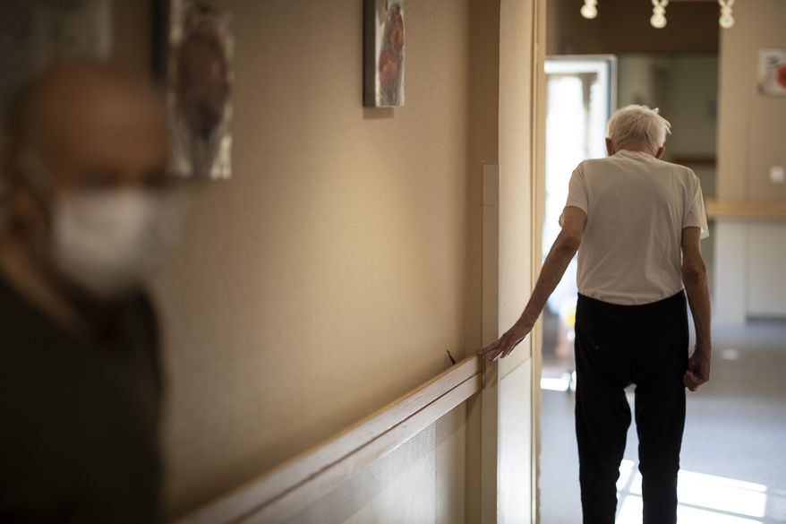 In this April 16, 2020, file photo, Richard Eberhardt walks along a corridor at a nursing home in Kaysesberg, France. Countries across Europe are struggling amid the coronavirus pandemic with the dilemma of leaving the elderly and others near death in enforced solitude or whether to allow some personal contact with relatives. At nursing homes, everything is done to keep out visitors who might be infected, and family members are almost always banned from coming to see their loved ones. (AP Photo/Jean-Francois Badias, File)
