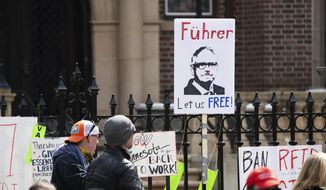 A sign comparing Minnesota Gov. Tim Walz to Adolph Hitler is held in front of the Governor&#39;s Mansion during a &amp;quot;Liberate Minnesota&amp;quot; protest in St. Paul, Minn., on Friday, April 17, 2020. (Evan Frost/Minnesota Public Radio via AP)