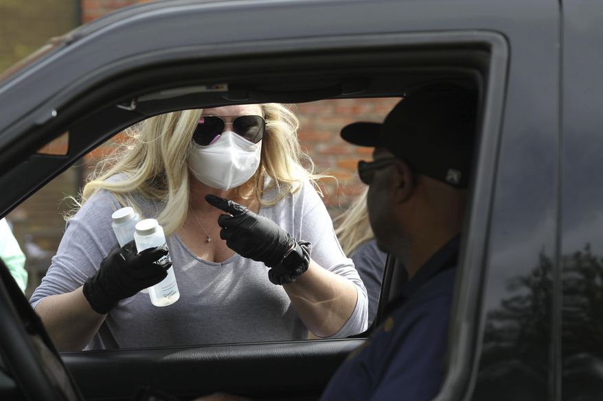 Lesley Scott of Saltillo Mississippi helps pass out free bottles of hand sanitizer from Queen's Reward Friday, April 17, 2020 in Tupelo, Miss. 1,000 bottles were purchased by Scott's fiance' John Weber, owner of Weber Marine in Baton Rouge La., the first 500 bottles were given out Friday with the remainder being distributed to Lee County Emergency personal and local postal carriers.(Thomas Wells/The Northeast Mississippi Daily Journal via AP)