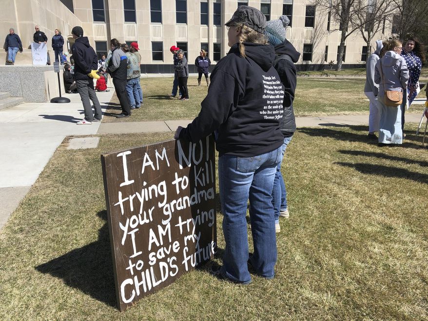 Protesters gather on the Capitol steps and grounds on Monday, April 20, 2020 in Bismarck, N.D. The group was protesting to show their opposition to Gov. Doug Burgum's order to keep most businesses closed until at least the end of the month in an effort to contain the spread of the coronavirus.(AP Photo/James MacPherson)