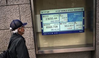 A man wearing a mask against the spread of the new coronavirus looks at an electronic stock board showing world stock indexes at a securities firm in Tokyo Tuesday, April 21, 2020. Asian shares skidded on Tuesday after U.S. oil futures plunged below zero as storage for crude runs close to full amid a worldwide glut as demand collapses due to the pandemic. (AP Photo/Eugene Hoshiko)