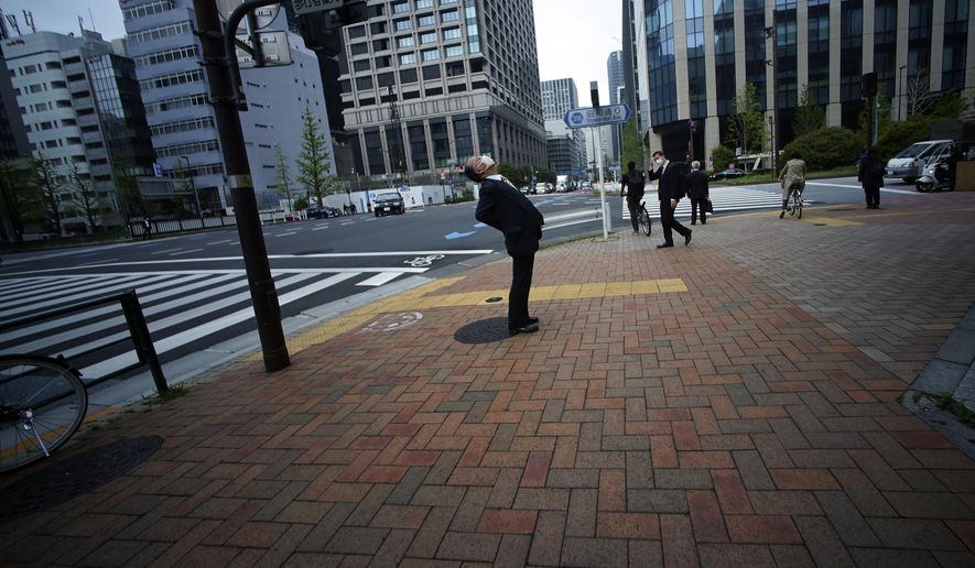 A man wearing a mask against the spread of the new coronavirus stretches at a business district in Tokyo Tuesday, April 21, 2020. Japan's Prime Minister Shinzo Abe expanded a state of emergency to all of Japan from just Tokyo and other urban areas as the virus continues to spread. (AP Photo/Eugene Hoshiko)