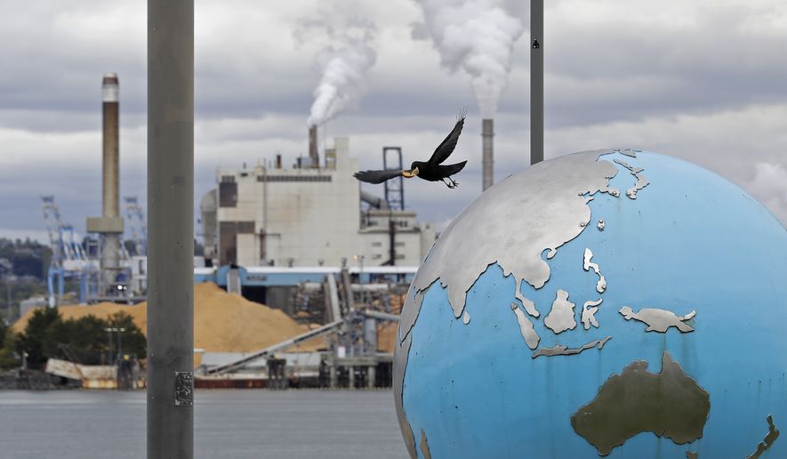 In this Tuesday, April 21, 2020, photo, a bird takes off from an Earth globe sculpture at Thea&#39;s Park in Tacoma, Wash., with the WestRock Paper Mill in the background. Wednesday is the 50th anniversary of Earth Day, an observance that helped spur activism against air and water pollution and disappearing plants and animals, but ongoing challenges remain throughout the world. (AP Photo/Ted S. Warren)