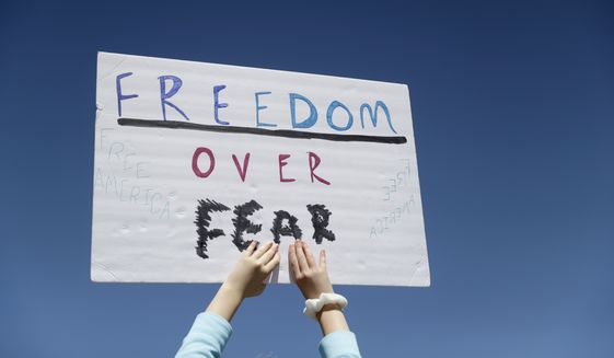A person holds a sign while gathering with others to protest stay-at-home orders put into place due to the COVID-19 outbreak outside the Missouri Capitol in Jefferson City, Mo, April 21, 2020. Amid pockets of attention-grabbing protests, a new survey finds Americans remain overwhelming in favor of stay-at-home orders and other efforts to slow the spread of coronavirus. (AP Photo/Jeff Roberson) ** FILE **