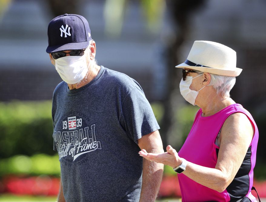 A couple takes COVID-19 precautions, donning facemasks during a leisurely stroll through downtown Winter Garden, Fla., Wednesday, April 22, 2020. Weather was near perfect for a walk, with highs in the low 80s and plenty of sunshine. (Joe Burbank/Orlando Sentinel)/Orlando Sentinel via AP)
