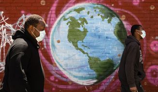 People wearing a protective face mask as a precaution against the coronavirus walk past a mural of the world in Philadelphia, Wednesday, April 22, 2020. April 22 is observed as Earth Day every year as a tool to raise ecological awareness. (AP Photo/Matt Rourke)