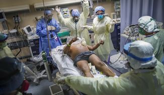 Nurses and doctors clear the area before defibrillating a patient with COVID-19 who went into cardiac arrest, Monday, April 20, 2020, at St. Joseph&#39;s Hospital in Yonkers, N.Y. The emergency room team successfully revived the patient. (AP Photo/John Minchillo)