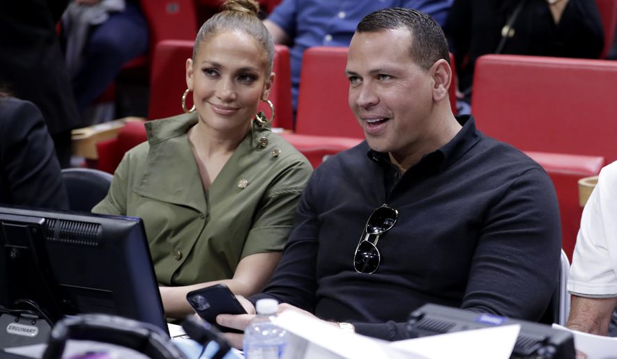 FILE - In this Dec. 13, 2019, file photo, Jennifer Lopez, left, and Alex Rodriguez sit courtside during an NBA basketball game between the Miami Heat and the Los Angeles Lakers in Miami. Rodriguez and Lopez have retained J.P. Morgan to represent them in raising capital for a possible bid for the New York Mets. The move was first reported by Variety and confirmed to The Associated Press by a person familiar with the decision who spoke on condition of anonymity because it was not announced. (AP Photo/Lynne Sladky, File)