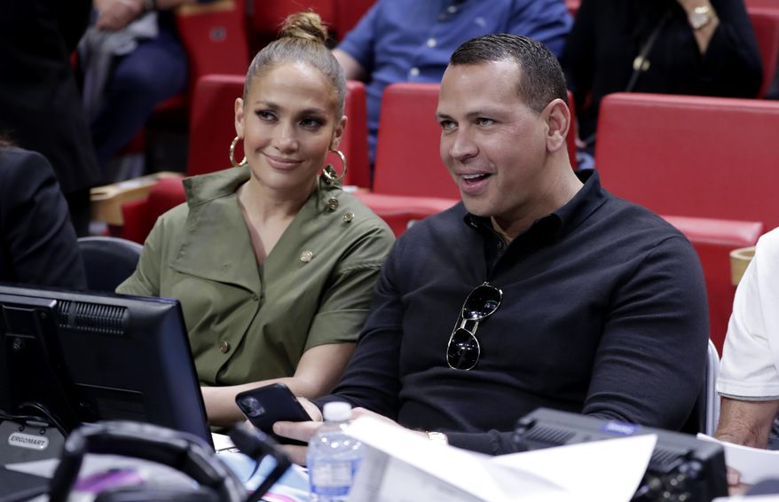 FILE - In this Dec. 13, 2019, file photo, Jennifer Lopez, left, and Alex Rodriguez sit courtside during an NBA basketball game between the Miami Heat and the Los Angeles Lakers in Miami. Rodriguez and Lopez have retained J.P. Morgan to represent them in raising capital for a possible bid for the New York Mets. The move was first reported by Variety and confirmed to The Associated Press by a person familiar with the decision who spoke on condition of anonymity because it was not announced. (AP Photo/Lynne Sladky, File)