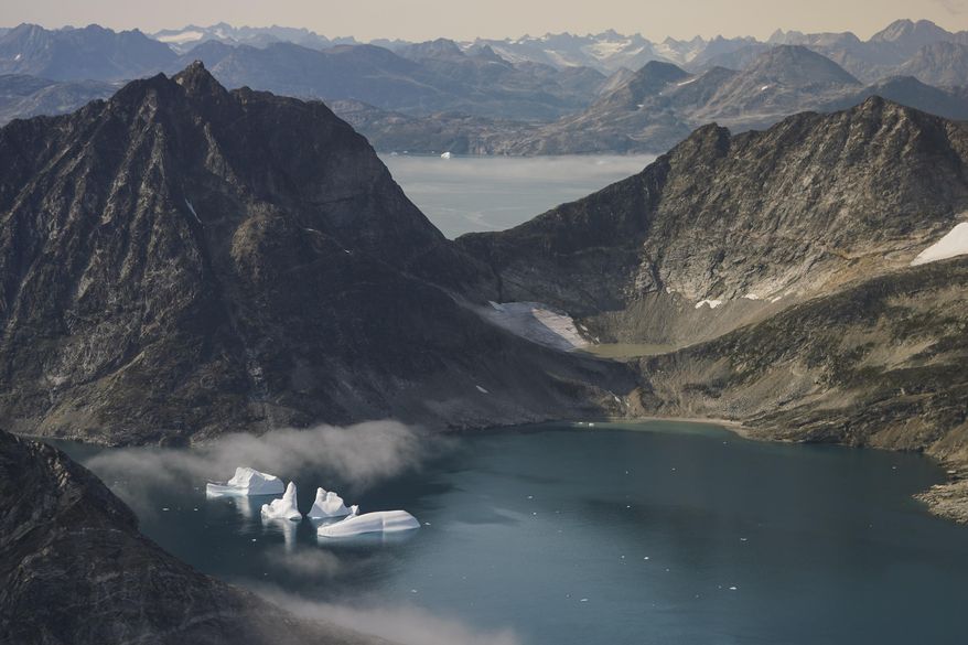 FILE - In this Aug. 14, 2019, file photo, icebergs are photographed from the window of an airplane carrying NASA scientists as they fly on a mission to track melting ice in eastern Greenland. The Trump administration is poised to announce an expanded diplomatic presence in Greenland and a new assistance package for the vast island aimed at thwarting growing Chinese and Russian influence in the Arctic. The announcement, expected Thursday, April 23, 2020, will come less than a year after President Donald Trump drew derision for expressing an interest in buying Greenland. (AP Photo/Mstyslav Chernov, File)