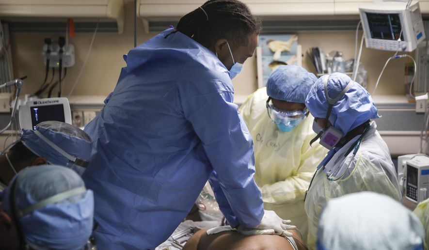 Nurses and doctors perform CPR on a patient with COVID-19 who went into cardiac arrest Monday, April 20, 2020, at St. Joseph&#x27;s Hospital in Yonkers, N.Y. The emergency room team successfully revived the patient. (AP Photo/John Minchillo)