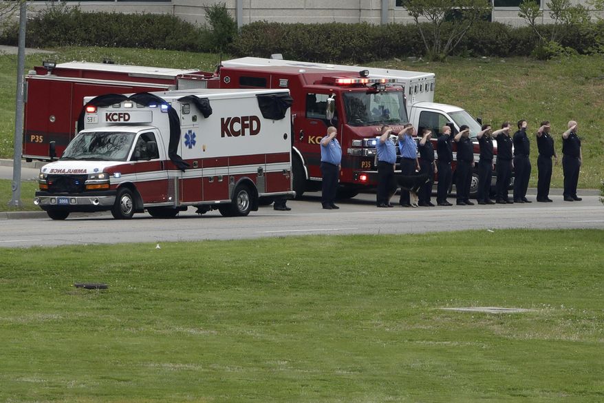An ambulance carrying the casket of Kansas City Fire Department EMT Billy Birmingham passes a fire station en route to the cemetery in Kansas City, Mo., Wednesday, April 22, 2020. Birmingham, who died after contracting COVID-19, was the first line-of-duty death among first responders in the state. (AP Photo/Charlie Riedel)