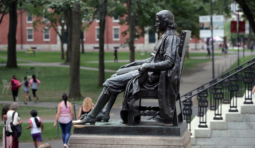 In this Aug. 13, 2019, file photo, students walk past the statue of John Harvard in Harvard Yard at Harvard University in Cambridge, Mass. (AP Photo/Charles Krupa, File)