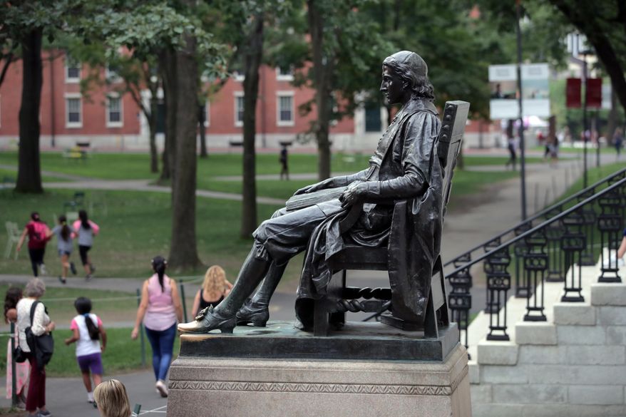 In this Aug. 13, 2019, file photo, students walk past the statue of John Harvard in Harvard Yard at Harvard University in Cambridge, Mass. (AP Photo/Charles Krupa, File)