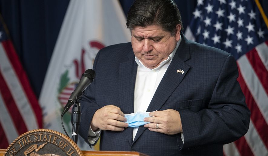 Gov. J.B. Pritzker puts away his face mask before delivering his daily Illinois coronavirus update at the Thompson Center, Thursday, April 23, 2020, in Chicago. (Tyler LaRiviere/Chicago Sun-Times via AP)