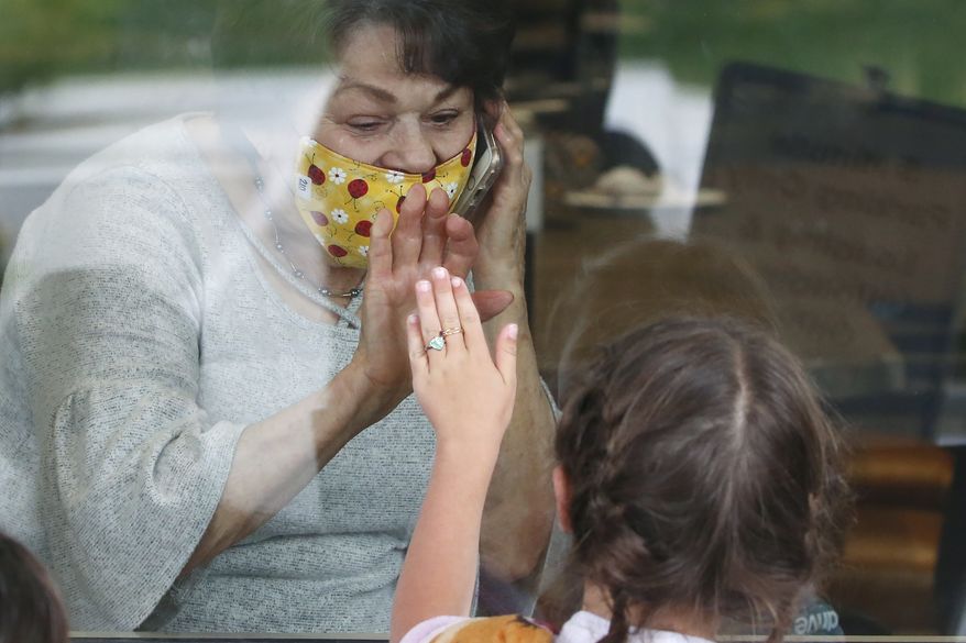 Raelene Critchlow, 86, receives a visit from her great-grandchild Camille Carter, 6, at Creekside Senior Living, Thursday, April 23, 2020, in Bountiful, Utah. Window visits help seniors connect to families despite coronavirus restrictions. (AP Photo/Rick Bowmer)