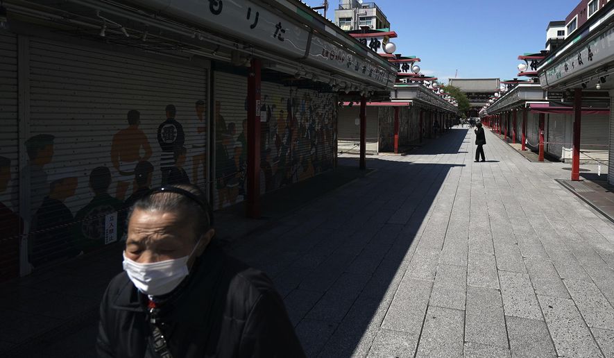 A woman wearing a mask to help stop the spread of the new coronavirus walks at usually crowded shopping arcade near Sensoji Temple in Tokyo Thursday, April 23, 2020. Japan's Prime Minister Shinzo Abe expanded a state of emergency to all of Japan from just Tokyo and other urban areas as the virus continues to spread. (AP Photo/Eugene Hoshiko)