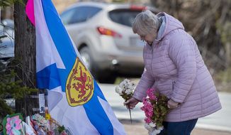 A woman pays her respects at a roadside memorial in Portapique, Nova Scotia on Thursday, April 23, 2020. Royal Canadian Mounted Police say multiple people are dead after a man who at one point wore a police uniform and drove a mock-up cruiser, went on a murder rampage in Portapique and several other Nova Scotia communities. (Andrew Vaughan/The Canadian Press via AP)