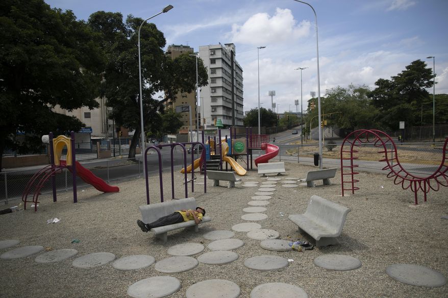 A man sleeps on a bench at a deserted playground amid a nationwide quarantine to slow the spread of the new coronavirus, in Caracas, Venezuela, Tuesday, April 7, 2020. (AP Photo/Ariana Cubillos)