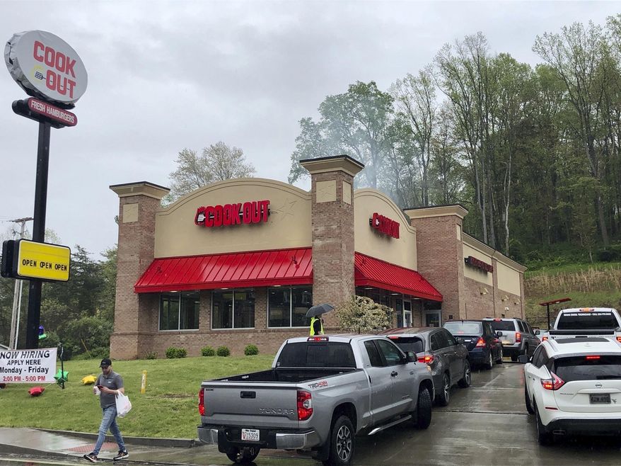 A customer leaves with a carry-out order at the newly opened Cook Out restaurant Thursday, April 23, 2020, in Cross Lanes, W.Va. The opening of the restaurant, which has drive-thru and carry-out window service only during the coronavirus pandemic, caused long lines and a significant traffic jams in the community of about 10,000 people. (AP Photo/John Raby)