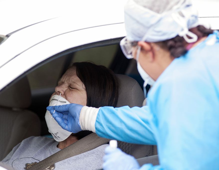 Regina Nelson, left, is tested for the coronavirus by Gina Johnson, a nurse tech, at the Bono Family Medical Clinic drive-thru testing site on Friday, April 24, 2020, in Bono, Ark. (Quentin Winstine/The Jonesboro Sun via AP)