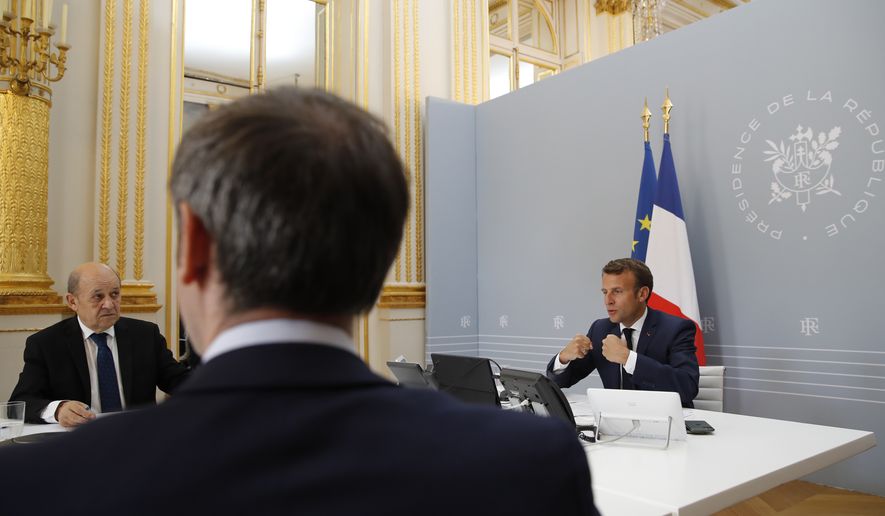 French President Emmanuel Macron, right, speaks with Tedros Adhanom Ghebreyesus, Director General of the World Health Organization and other world leaders about the coronavirus outbreak during a video conference at the Elysee Palace Friday, April 24, 2020 in Paris. Emmanuel Macron urged leaders of the world's biggest economies to "show the world that it's possible to succeed when we are all together and unite our forces." At left is French Foreign Minister Jean-Yves le Drian. (AP Photo/Christophe Ena, Pool) **FILE**
