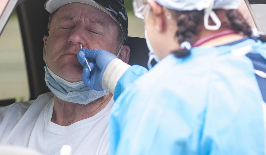 Kevin Nichols, left, is tested for the coronavirus by Gina Johnson, a nurse tech, at the Bono Family Medical Clinic drive-thru testing site on Friday, April 24, 2020, in Bono, Ark. (Quentin Winstine/The Jonesboro Sun via AP)