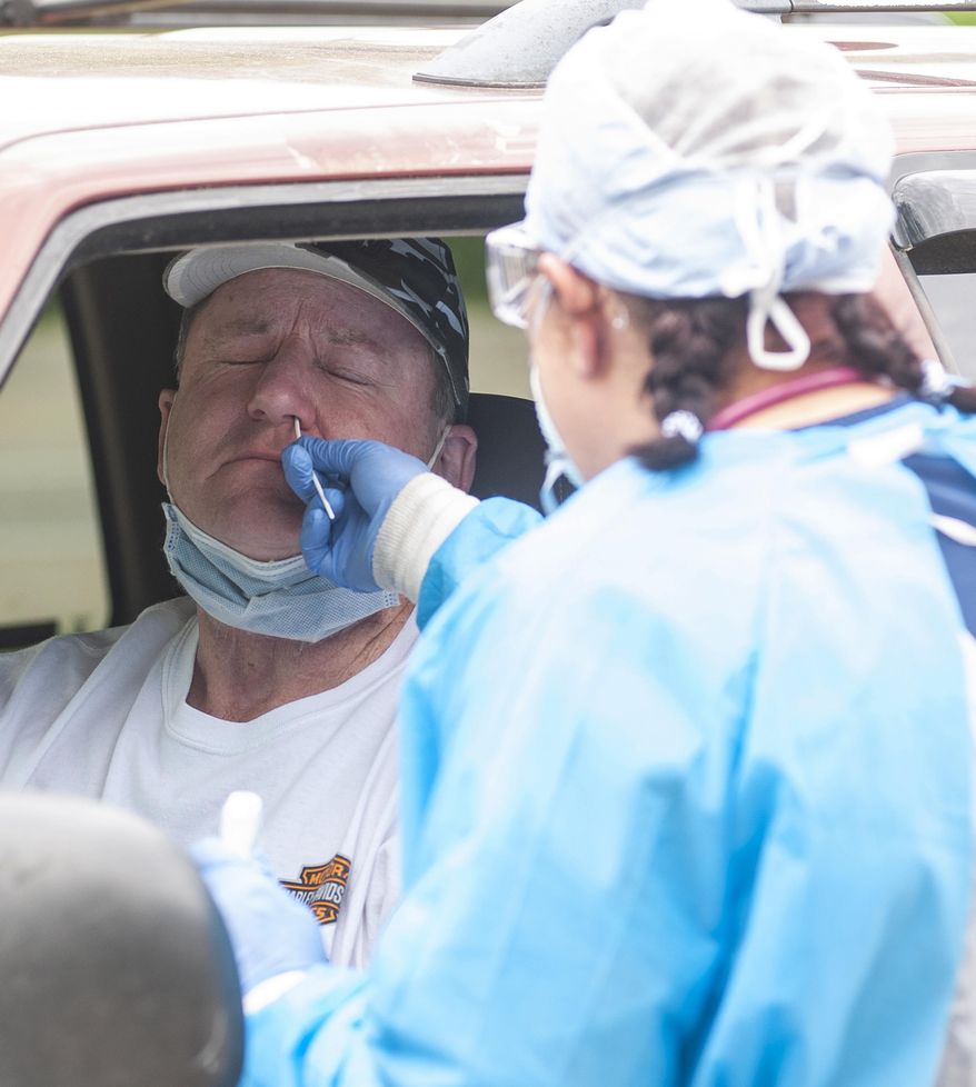 Kevin Nichols, left, is tested for the coronavirus by Gina Johnson, a nurse tech, at the Bono Family Medical Clinic drive-thru testing site on Friday, April 24, 2020, in Bono, Ark. (Quentin Winstine/The Jonesboro Sun via AP)