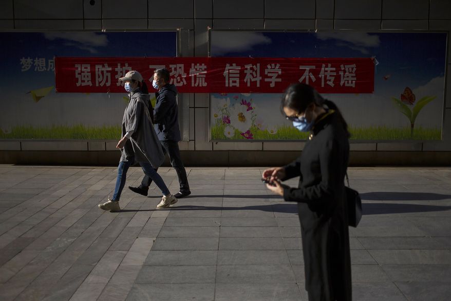 People wear face masks to protect against the spread of the new coronavirus as they walk along a street in Beijing, Thursday, April 23, 2020. China says Australian calls for an independent investigation into the cause of the coronavirus outbreak are politically motivated and unhelpful in dealing with the global pandemic. (AP Photo/Mark Schiefelbein)