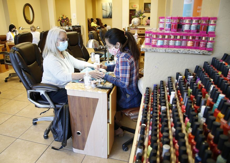 Lorri Center, left, has her nails done by Trish Ho at BA Nail & Spa in Broken Arrow, Okla., on Friday, April 24, 2020. The shop was among several allowed to reopen in a loosening of coronavirus-related restrictions. (Matt Barnard/Tulsa World via AP)