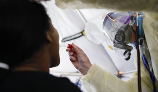 In this April 20, 2020 photo, Catherine Hopkins, Director of Community Outreach and School Health at St. Joseph&#39;s Hospital, right, performs a test on a patient in a COVID-19 triage tent at St. Joseph&#39;s Hospital in Yonkers, N.Y. New York’s plan for taming the coronavirus hinges on taking a time-tested practice to an extraordinary level: hiring an “army” of people to try to trace everyone who might be infected. It&#39;s part of a common approach to controlling infectious diseases -- testing, tracing contacts and isolating those infected. But the scope is staggering even for a public health system that used the technique to combat AIDS and tuberculosis. (AP Photo/John Minchillo)