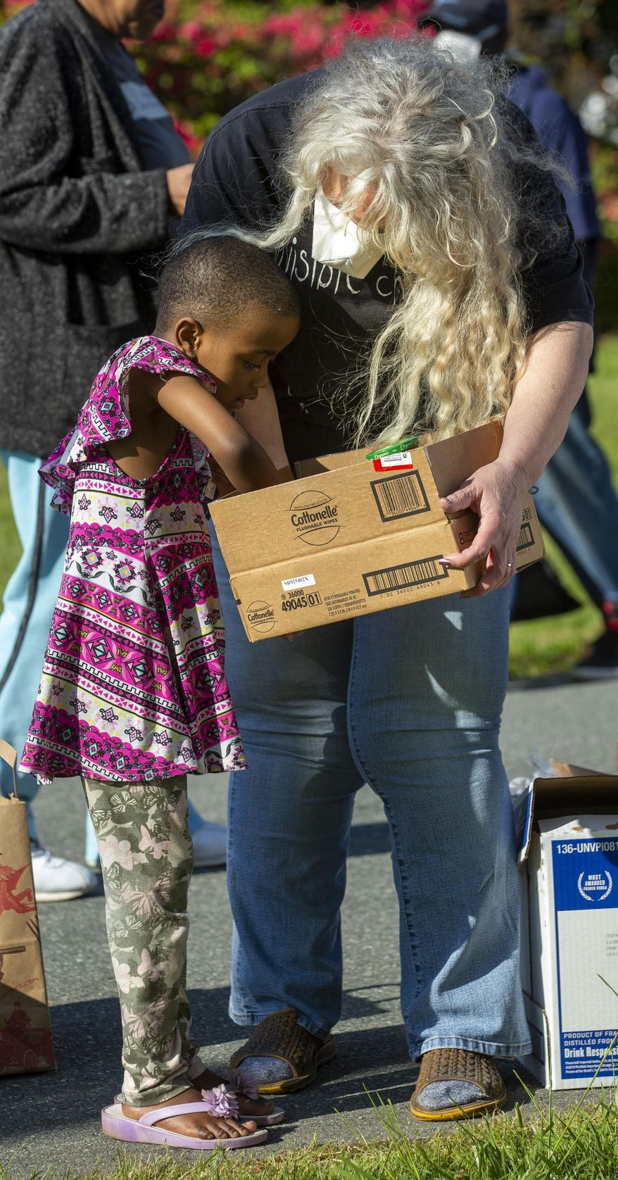 Char Lehew helps a child find food in a north Greensboro, N.C., neighborhood on Monday, April 20, 2020. (Woody Marshall/News & Record via AP)