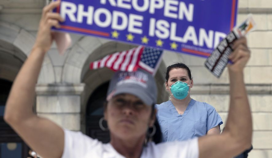A nurse stands in counter-protest during a demonstration against stay-at-home orders due to coronavirus concerns at the State House, Saturday, April 25, 2020, in Providence, R.I. (AP Photo/Michael Dwyer)
