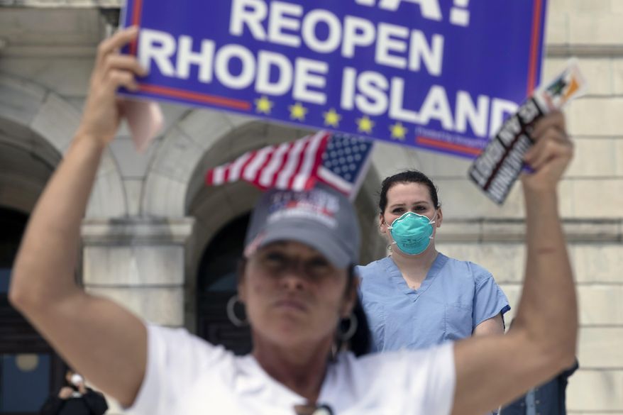 A nurse stands in counter-protest during a demonstration against stay-at-home orders due to coronavirus concerns at the State House, Saturday, April 25, 2020, in Providence, R.I. (AP Photo/Michael Dwyer)