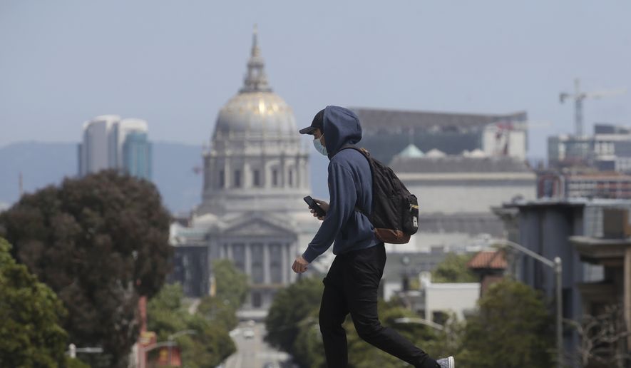 A man wears a face mask while walking in front of City Hall in San Francisco, Sunday, April 26, 2020, during the coronavirus outbreak. (AP Photo/Jeff Chiu)