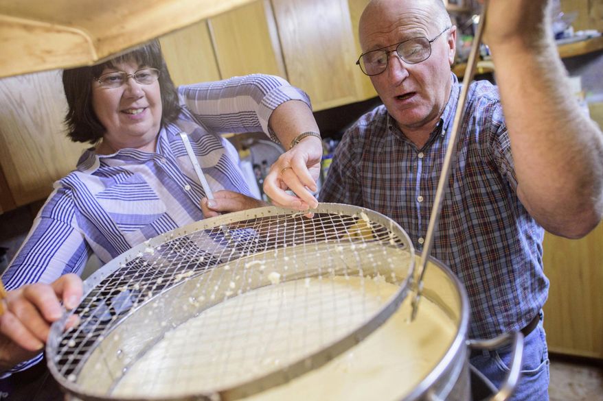 FILE - In this Sept. 20, 2017, file photo, Shari, left, and Dane Lambson pull out a curd cutter from a large pot of curdled milk at their home in Ramah, N.M. The COVID-19 pandemic is choking New Mexico's dairy market, forcing many farmers to throw surplus milk into irrigation ponds. (Adron Gardner/Gallup Independent via AP)