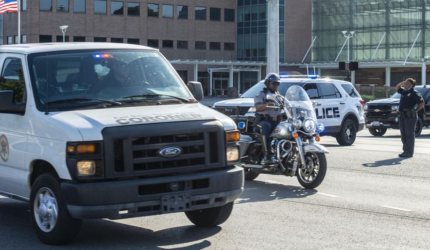 An officer salutes a motorcycle escort and a coroner's van carrying the body of a Baton Rouge police officer who was fatally shot, Sunday afternoon, April 26, 2020, in Baton Rouge, La. The shooting left one police officer dead and a wounded colleague fighting for life Sunday, authorities said, adding a suspect was in custody after an hourslong standoff at a home. Baton Rouge Police Chief Murphy Paul told The Advocate the officers were shot in the northern part of the city, and one of the officers later died. (John Ballance/The Advocate via AP)