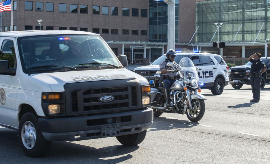 An officer salutes a motorcycle escort and a coroner's van carrying the body of a Baton Rouge police officer who was fatally shot, Sunday afternoon, April 26, 2020, in Baton Rouge, La. The shooting left one police officer dead and a wounded colleague fighting for life Sunday, authorities said, adding a suspect was in custody after an hourslong standoff at a home. Baton Rouge Police Chief Murphy Paul told The Advocate the officers were shot in the northern part of the city, and one of the officers later died. (John Ballance/The Advocate via AP)