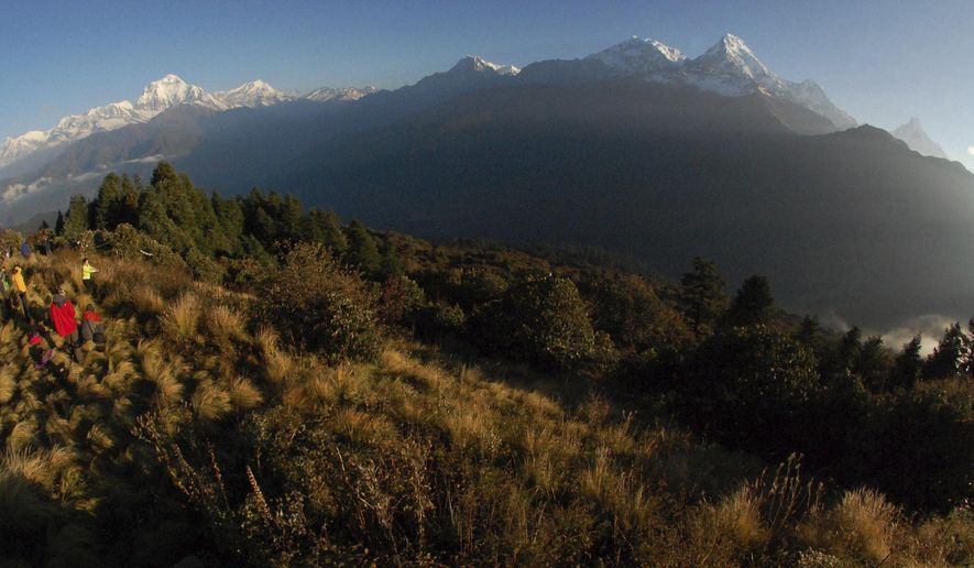 In this Oct. 24, 2014, file photo, trekkers watch the sun rise over the Annapurna Range, right, in central Nepal, as viewed from Poon Hill, above the village of Ghorepani. Rescuers on Sunday, April 26, 2020, recovered the bodies of two South Korean trekkers who were missing since January when an avalanche buried them in Nepal’s mountains, officials said. An army helicopter flew the bodies of one male and one female to Pokhara from the Annapurna Trekking Circuit, said Nepalese army official Maj. Gen. Gokul Bhandari. (AP Photo/Malcolm Foster, File)