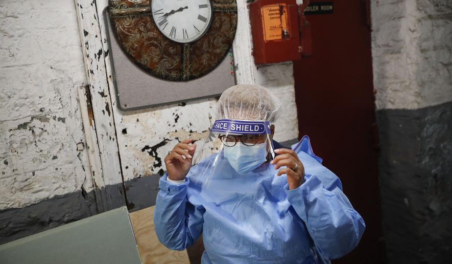 In this Thursday, April 23, 2020 photo, Ruth Caballero, a nurse with The Visiting Nurse Service of New York, suits up in protective equipment before treating a COVID-19 patient on her rounds in upper Manhattan in New York. Home care nurses, aides and attendants, who normally help an estimated 12 million Americans with everything from bathing to IV medications, are now taking on the difficult and potentially dangerous task of caring for coronavirus patients. (AP Photo/John Minchillo)