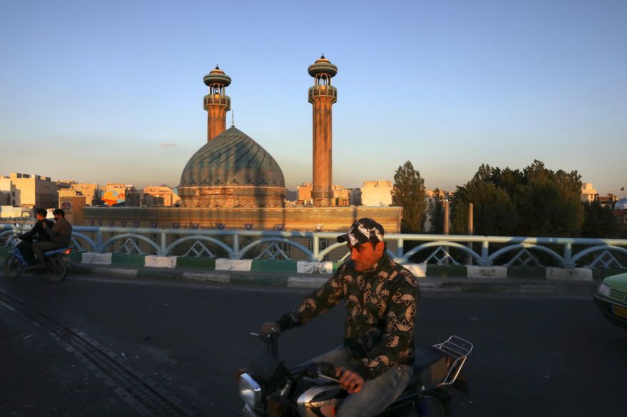 A man drives past a mosque on his motorcycle during the Muslim holy fasting month of Ramadan, in southern Tehran, Iran, Monday, April 27, 2020. In Iran, the country that is hit worst in the Middle East by the coronavirus, all religious gathering, congregational prayers and communal Iftar servings, a meal eaten at sunset to break the fast, remain forbidden in the Ramadan and also holy shrines and religious centers also continue to be closed until at least May 4. (AP Photo/Vahid Salemi)